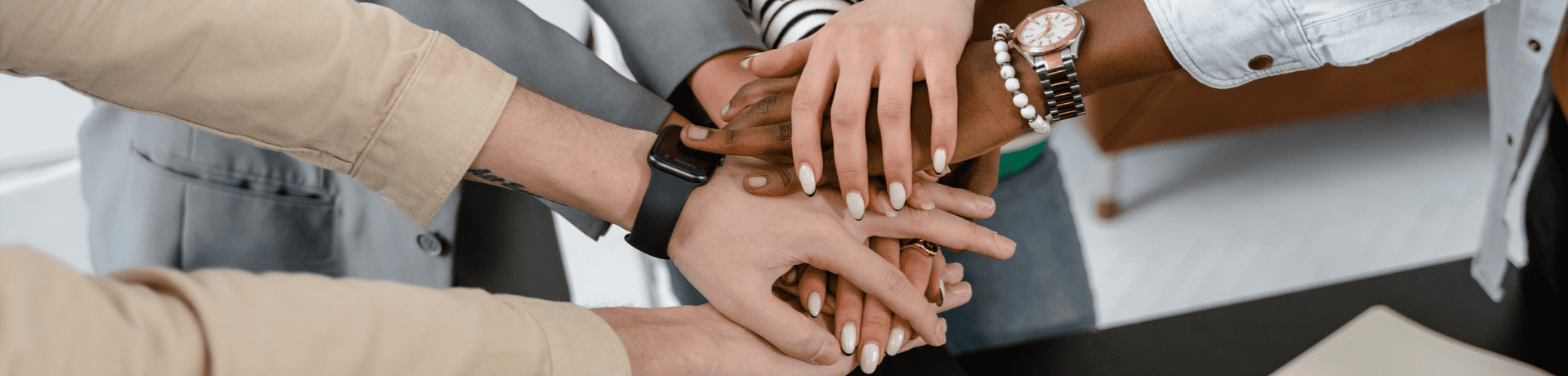 Hands all gathered in a circle, showing that they are all coming together as a team