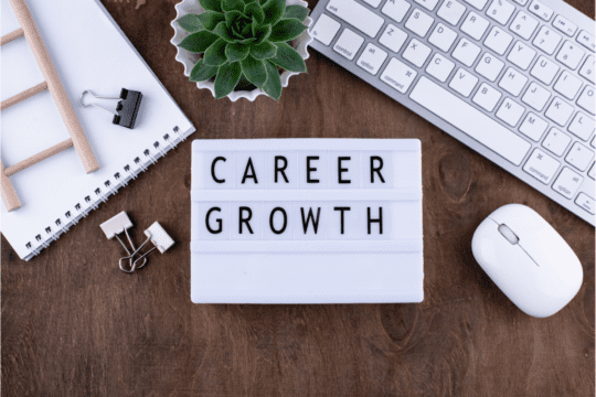 image with a keyboard, flower plant and board with the words " career growth" written on it