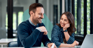 Two project management professionals reviewing documents smiling.